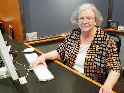 Kathy Barrett, a 45-year veteran of the Information Office at MIT, sits at the front desk to the office recently as her retirement date approaches.