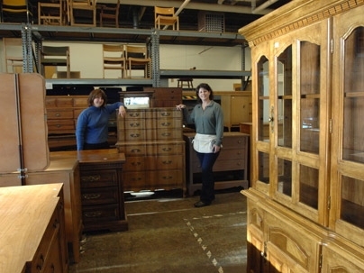 Furniture Exchange volunteer Laura Fuller, left, and manager Judy Halloran, right, stand amidst some of the wonders available at the Exchange for members of the MIT community.
