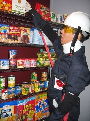 In the AGNES suit, engineering student Nathaniel Salazar reaches for a product on the top of a grocery shelf in the AgeLab.