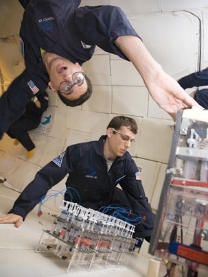 MIT senior Arya Tafvizi and graduate student Thomas Coffee work on an aerogel experiment in the microgravity.