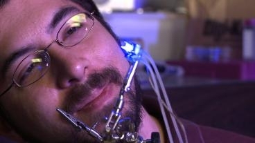 Ed Boyden holding his most recent optogenetic device; an array of optical elements that can turn on and off individual neurons in sixteen different points with the brain.
