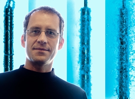 Professor Jacopo Buongiorno; background image shows a dispersion of nanoparticles in water that accelerates quenching of a hot rodlet (simulating a nuclear fuel rod), a feature that may be used to improve the thermal performance of nuclear reactors.