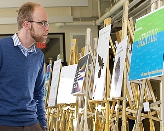 Mikhail Wolfson, a graduate student in the Department of Chemistry, looks at the poster contest entries outside the Pappalardo Room.