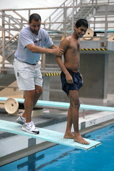 Larry Anderson, instructor for beginning swim class, guides Srikanth Bolla ’13 to the end of the diving board. 