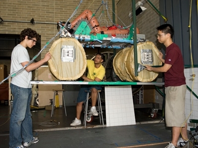 Do and two colleagues prepare the system and dummy for a drop test. During these drops, the accelerations experienced by the dummy can be measured to determine the level of injury a human might experience.
