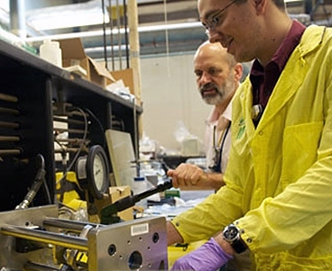Gordon Kohse, left, and David Carpenter prepare an apparatus for burst testing of irradiated silicon carbide composite tubes in a radioactive materials laboratory at the Nuclear Reactor Laboratory.