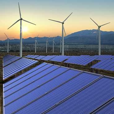 Solar panels in a field with wind turbines in the distance