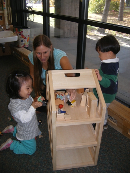Karen Mikita, lead teacher at TCC Westgate, works with two preschool students engaged in dramatic play.