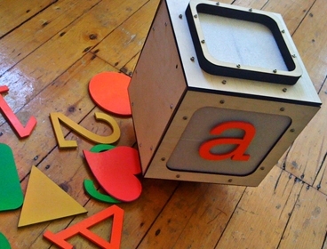 The Alphabot, a prototype robot that appears to move seamlessly between the real world and an on-screen virtual world, is designed to resemble a child's alphabet block.