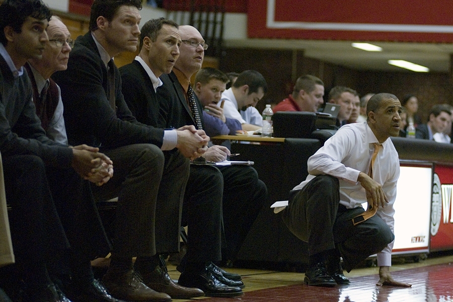 Head coach Larry Anderson, right, crouches on the sideline as his coaching staff watches during the final minutes against Springfield. From left: assistant coach Indran Ratnathicam ’98; Dean for Undergraduate Research Kim Vandiver '69, PhD '75; assistant coach and former NBA player Paul Grant; assistant coach Rob DiBernardo; and associate head coach Kevin Byrne.