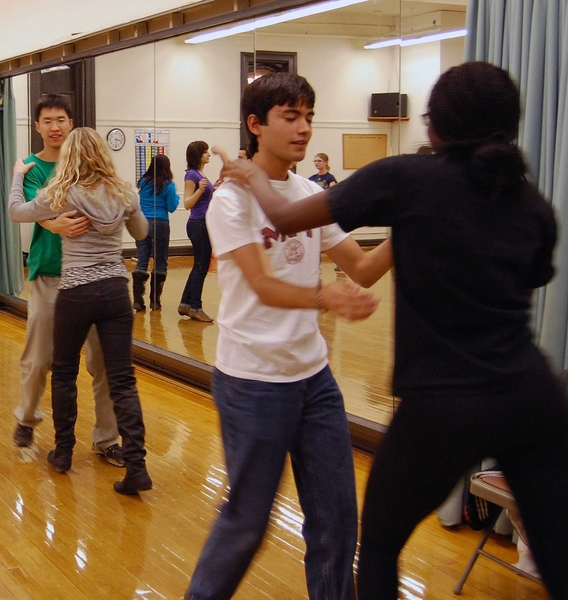 Students pair off to practice their steps during salsa class.