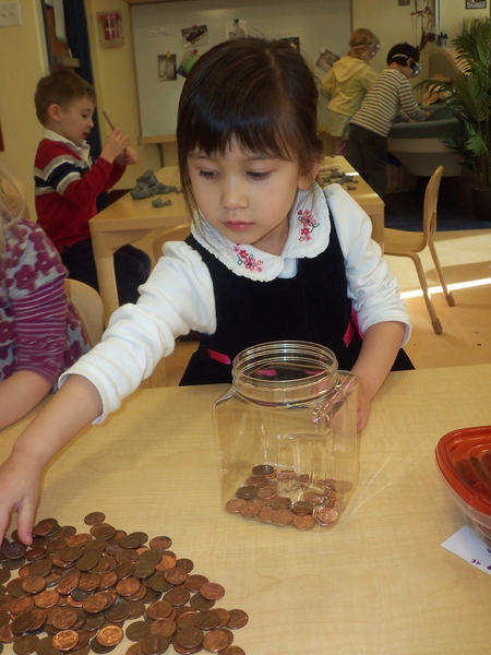 A preschooler at the Stata Technology Children's Center practices counting to 150 by counting pennies.