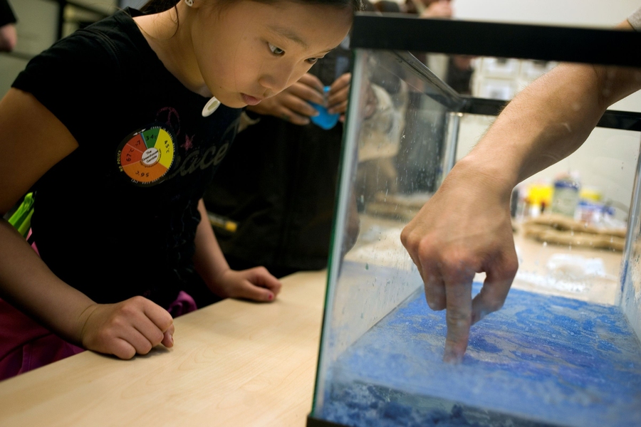 Julie Park, 9, of Natick, Mass., watches a demonstration of 'magic sand,' a hydrophobic substance, demonstrated by Satoru Emori, a graduate student in the Department of Materials Science and Engineering.