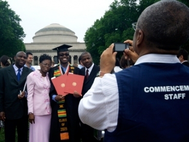 A Commencement volunteer takes a picture of a graduate and his family at the 2009 Commencement ceremonies.