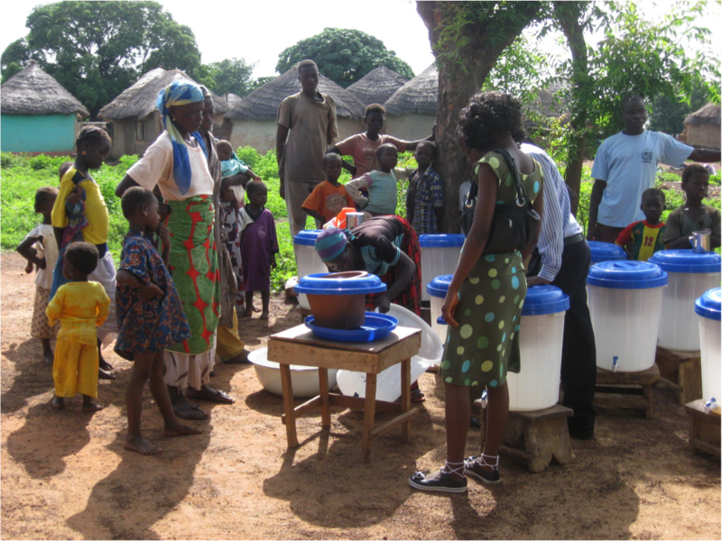 Villagers are shown how to use and maintain the filter systems, which include a porous clay pot inside a plastic bucket.