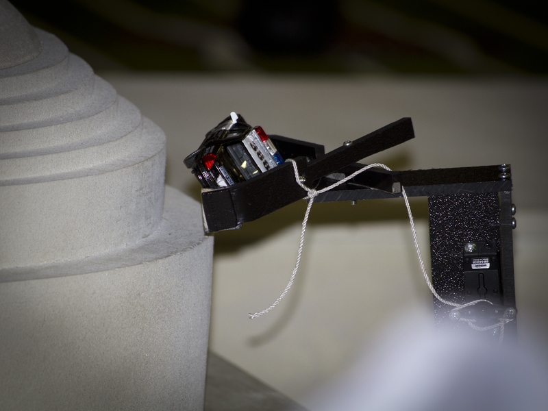 One of the robots carefully places the police car on the dome.