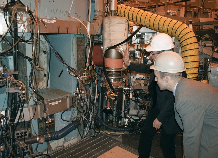 Massachusetts State Senator Benjamin Downing (foreground) peers into a port of the Alcator C-Mod tokamak to see the vacuum chamber where fusion reactions take place, guided by Alcator Project Head Earl Marmar.