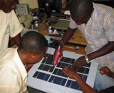 Takorardi Technical Institute students hot-glue assembled solar cells onto a 30W panel, which was installed in a neighboring village.