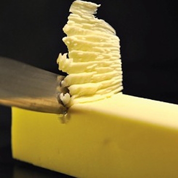 Sharp object skims off top of yellow block, forming a stack of soft residue.