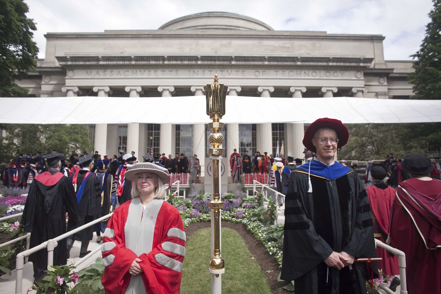 Alumni Association President Anne Street, left, and faculty marshal Stephen Graves stand at the front of the main stage as faculty fill Killian Court.