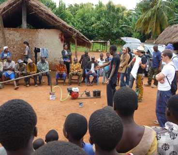 Members of a team that developed a system for generating gas from agricultural waste, which is attached to a small engine to generate power for charging cellphones, demonstrate their prototype at a village in Ghana.