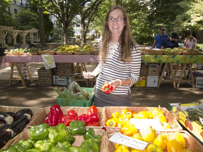 Graduate student Ann Bauer soaks up the sunshine and loads up her basket with fresh vegetables at the MIT Produce Market at East Campus.