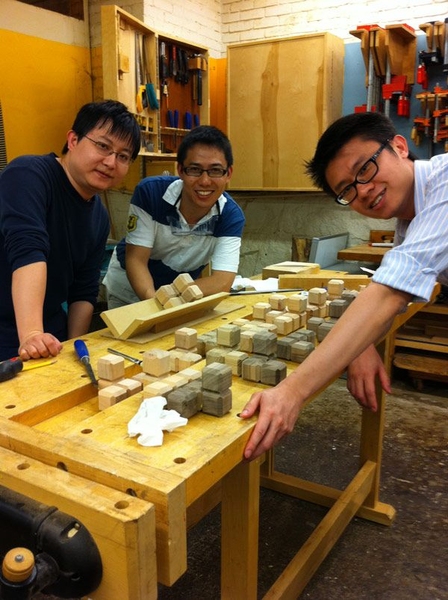 Singapore University of Technology and Design assistant professors Jason Gu, Sun Jun and Chau Yuen built wooden cube puzzles in an introduction to the MIT Hobby Shop. MIT announced a new collaborative effort with SUTD in January.