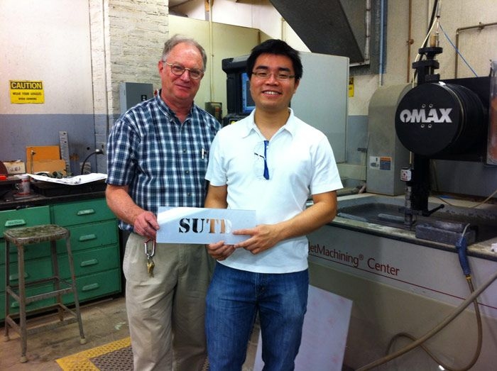 Stone taught Shaohui to use computer software and a water jet to carve “SUTD” into a metal sheet.