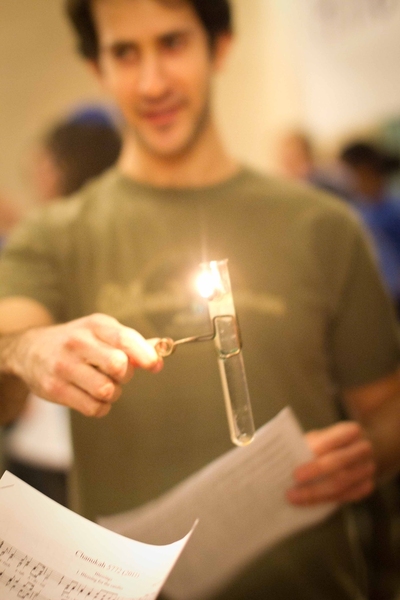 Preparing to illuminate the menorah, senior Zach Stauber holds the shamash, the test tube designated to light the others.