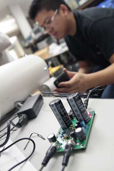 Senior Steven Lam listens to his finished speakers. In the foreground sits a student-built digital switch-mode amplifier.