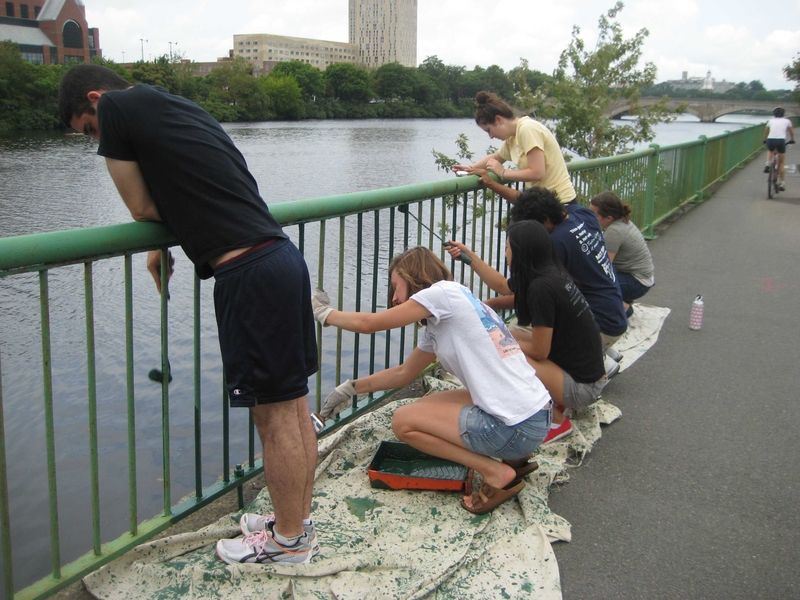 Freshman Urban Program counselors paint a fence with the Charles River Conservancy.