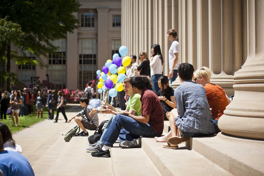 Community members enjoy their lunch in the sun on the steps of Killian Court.