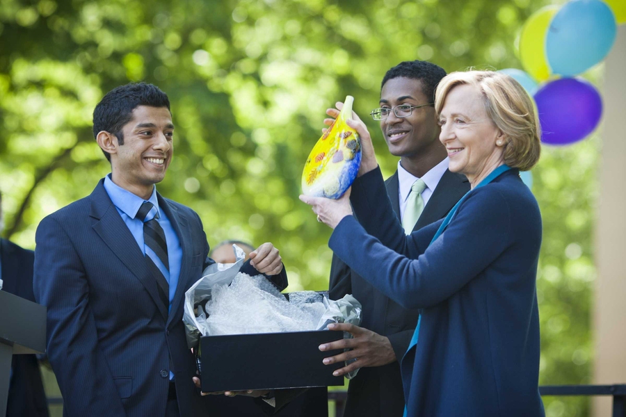 Aalap Dighe, left, the vice president of the Graduate Student Council, and TyShaun Wynter, former president of the Undergraduate Association, present Hockfield with a brightly colored vase from MIT's Glass Lab.