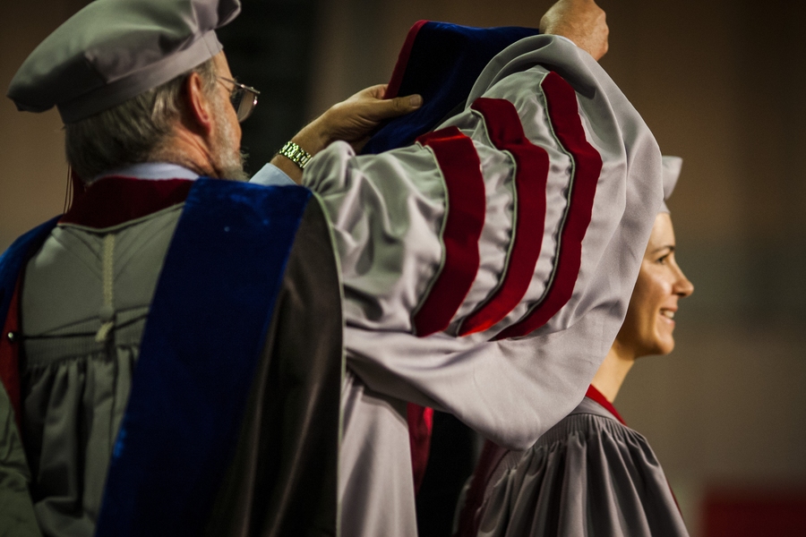 Doctoral students receive their hoods from administrators and faculty from their school, department or program.