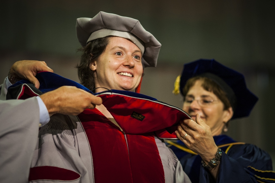 Doctoral students receive their hoods from administrators and faculty from their school, department or program.