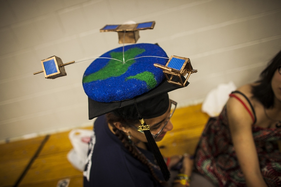 MIT students take pride in adorning their caps with various decorations. Here, a student has turned her cap into Earth, surrounded by satellites.
