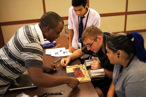 Instructor Raoul Ouedraogo (left) shows the students the proper wiring needed on a circuit board for their self-built radar.