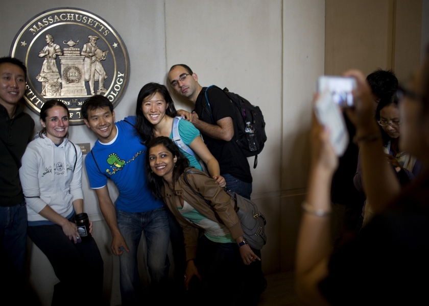 Community members take a photo in front of a replica of the MIT seal that is housed in Lobby 7.