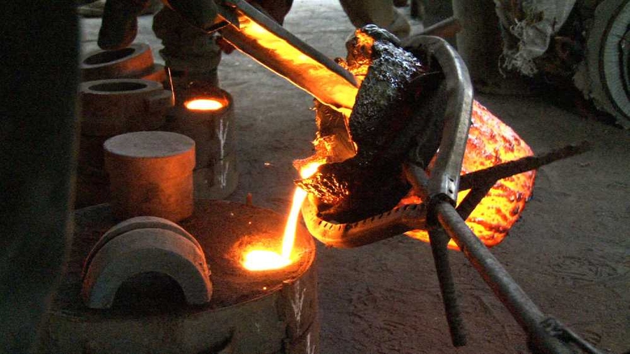 D-Lab Scale-Ups fellow Kwami Williams ('12) and Ghanaian master blacksmith Stone Musah at work in Ghana pouring molten cast iron into a mold to create an auger. The auger was incorporated into a press used to extract oil from Moringa seeds.