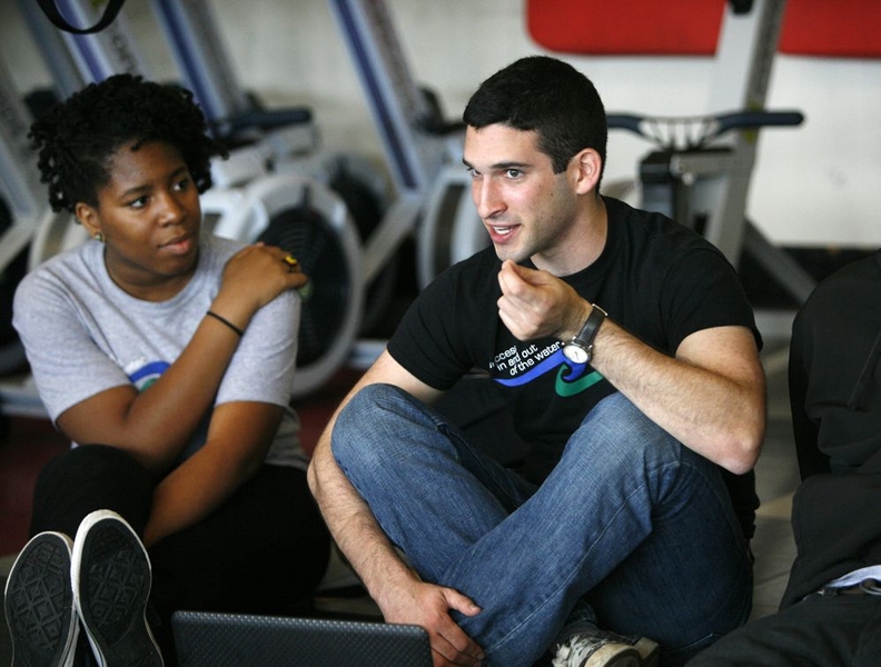 MiKhai Edwards, left, listens intently as MIT senior Noam Angrist talks about his motivation for rowing in preparation for the day's five-minute piece — a timed rowing trial where Amphibious Achievers push themselves past their limit to break their personal records.