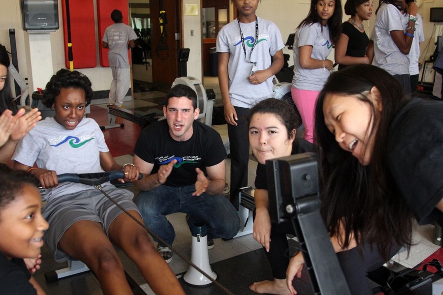 Amphibious Achievers' coaches Noam Angrist, Alice Huang, middle, and Sixing Zhao, right, cheer on Achiever Chalayna Smart as she nears the end of the team relays, a key part of every practice, where teams of four compete to row 400 meters in the fastest time.