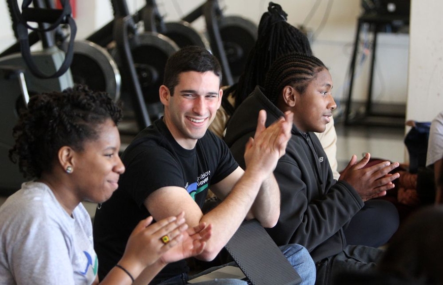 Achievers MiKhai Edwards, left, Brandon Bennett, right, and Coach Angrist clap loudly for one of the Achievers as Angrist announces the big news: more Achievers broke their personal records on the five-minute timed trial on Sunday than they ever had in Amphibious Achievement history.