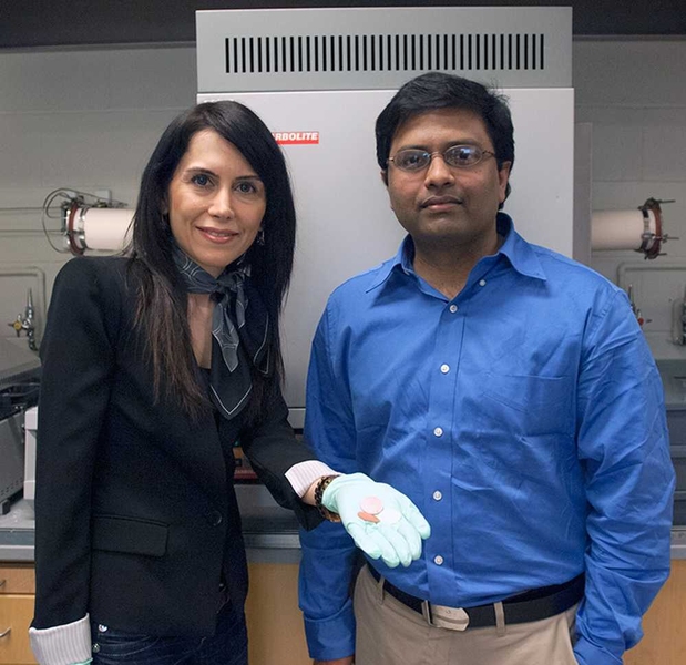 MIT postdoc Gisele Azimi, left, displays three of the 13 different ceramic disks made from oxides of the rare earth elements, with associate professor Kripa Varanasi. Behind them is the furnace used to convert the powdered oxides into solid ceramic form.