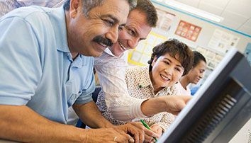 Four people near a computer monitor in classroom