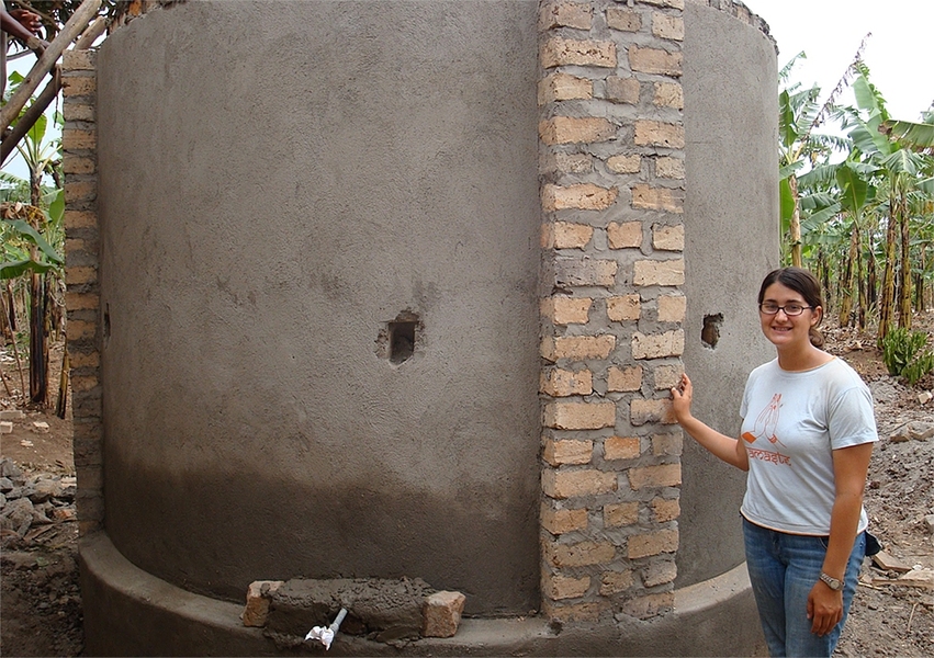 Simmons poses next to a rainwater harvesting tank in Ddegeya, Uganda.