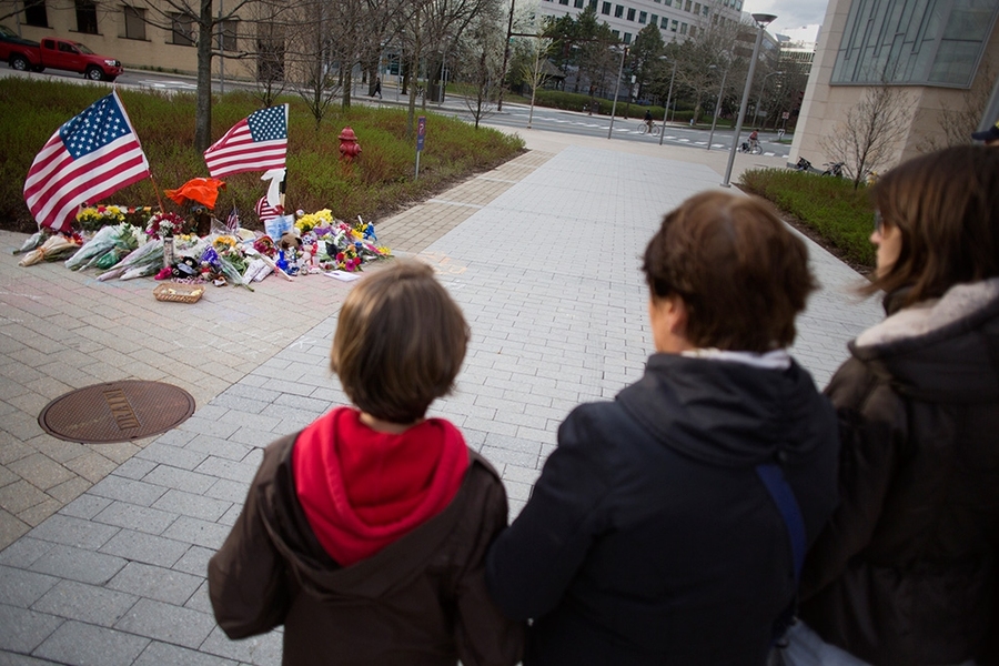 A group stops and pays respect near the memorial.