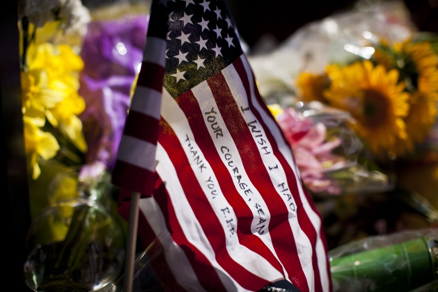 The memorial includes flowers, personal notes, flags and MIT Police regalia.