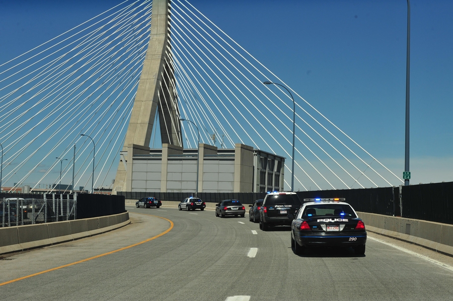 Police drive by the Zakim Bridge in Boston on their way to the memorial ceremony.