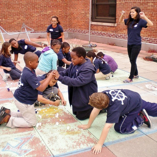 MITxplorers build skyscrapers with spaghetti and marshmallows under the encouragement of co-president and mentor Debbie Nguyen (right).