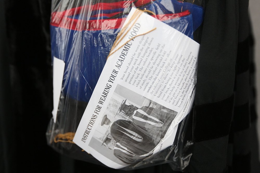 A bag filled with graduation regalia includes instructions on how to appropriately wear it.
